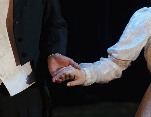 A close-up shot of a man and woman holding hands